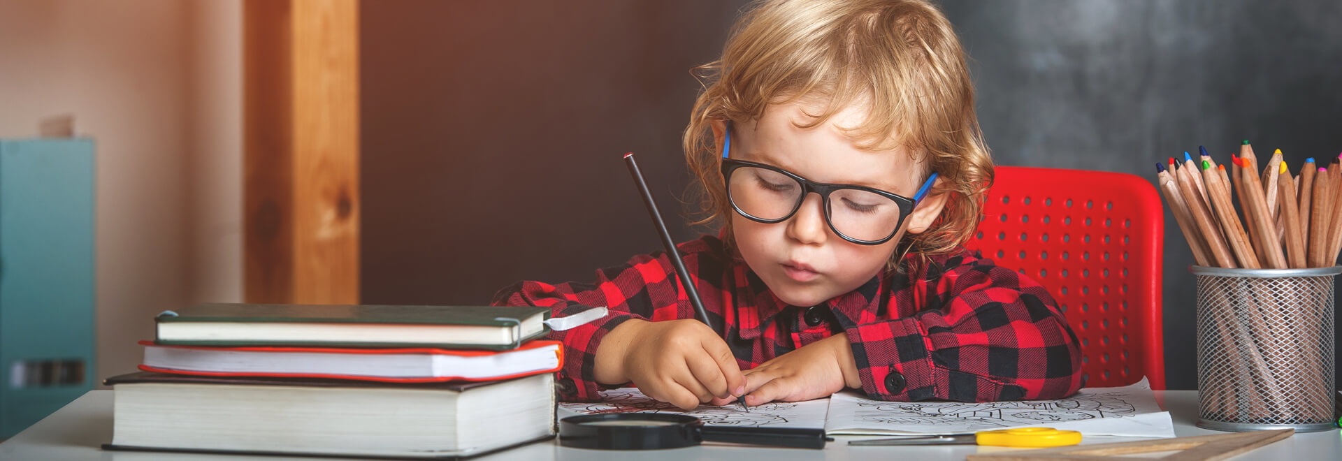 طفل يقوم بالرسم والتلوين مرتديا قميص احمر